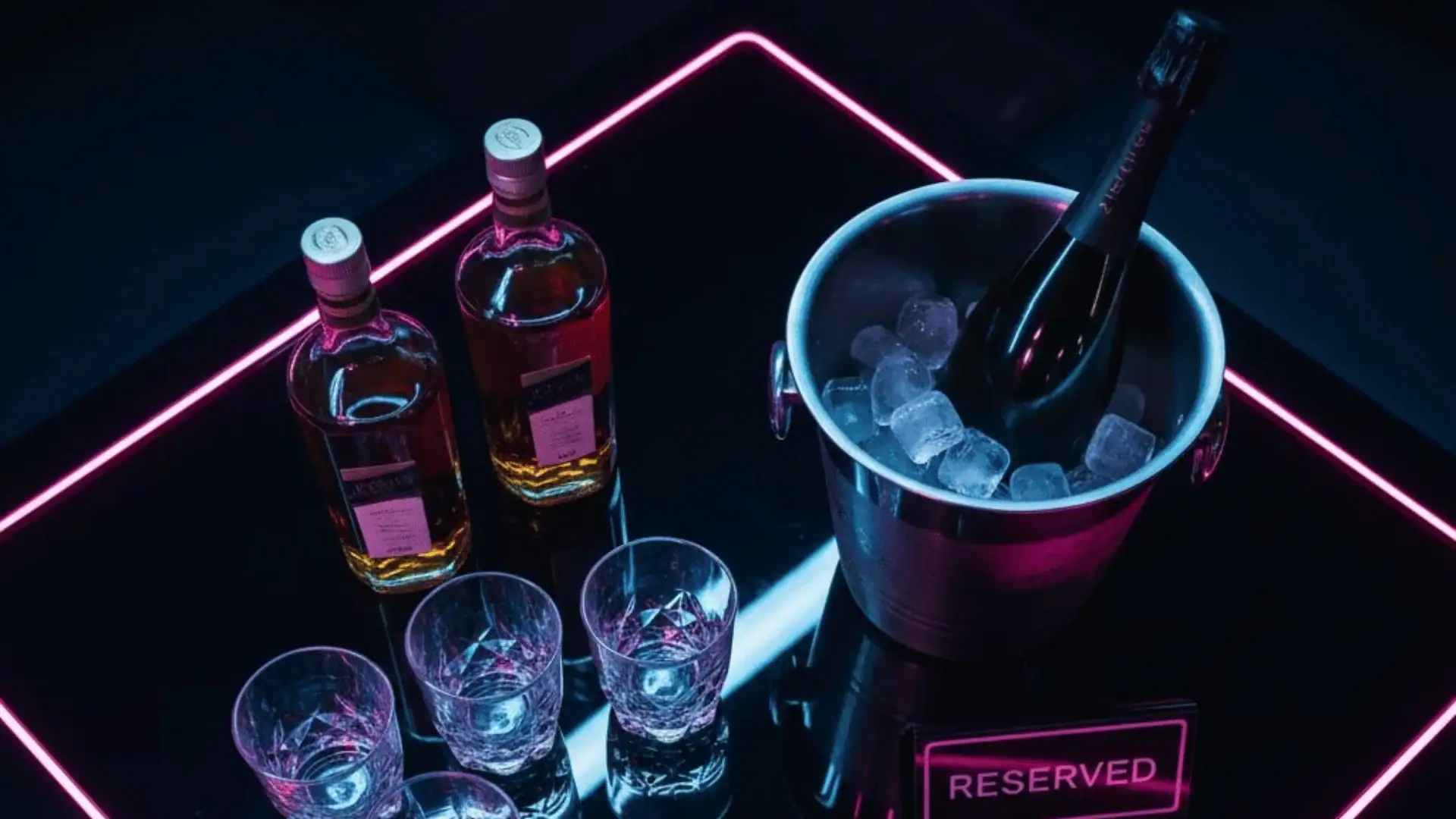 Champagne and whiskey displayed on a glowing neon-lit table inside Atlantis of NYC in Jamaica, NY.